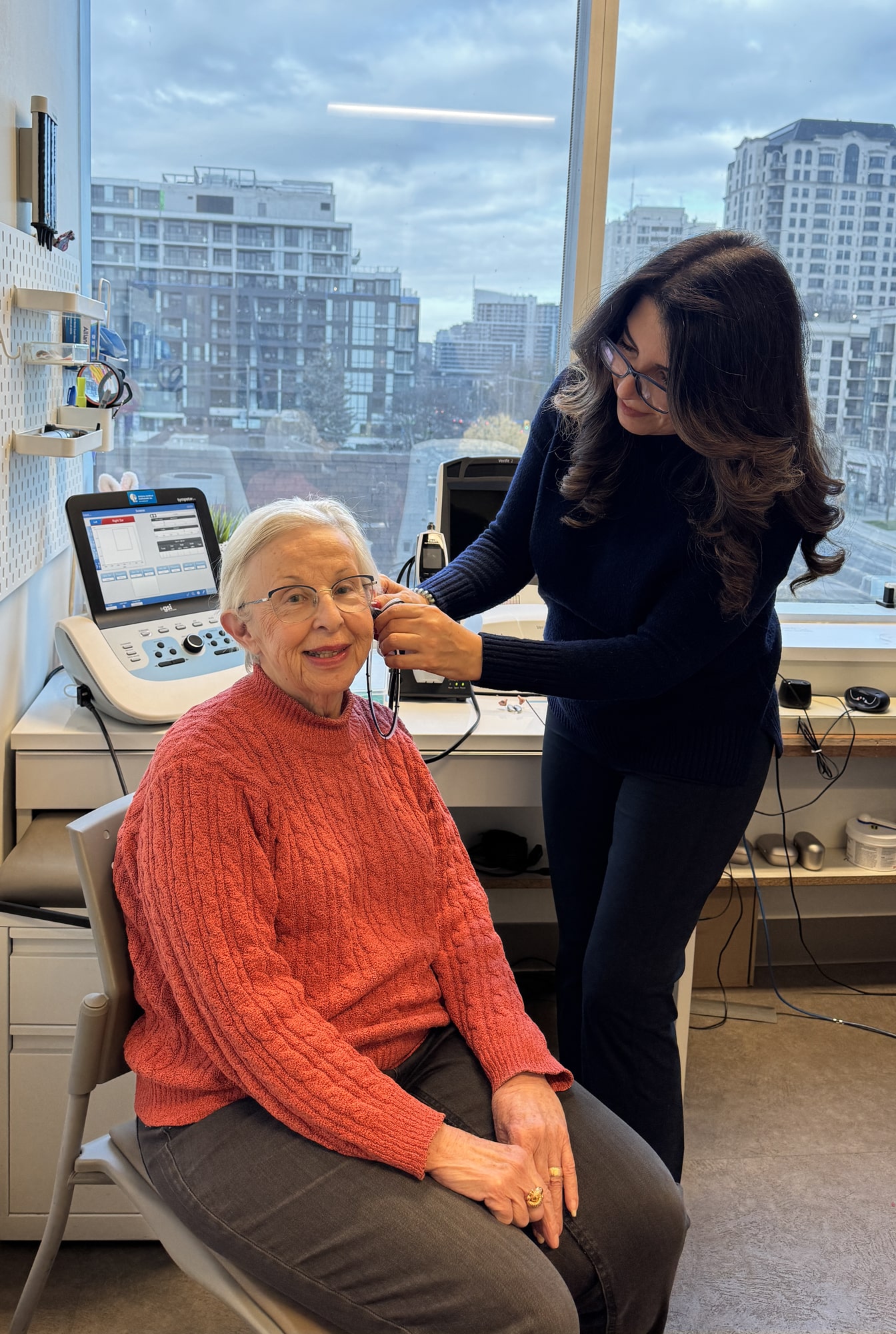 hearing provider checking ear of older woman