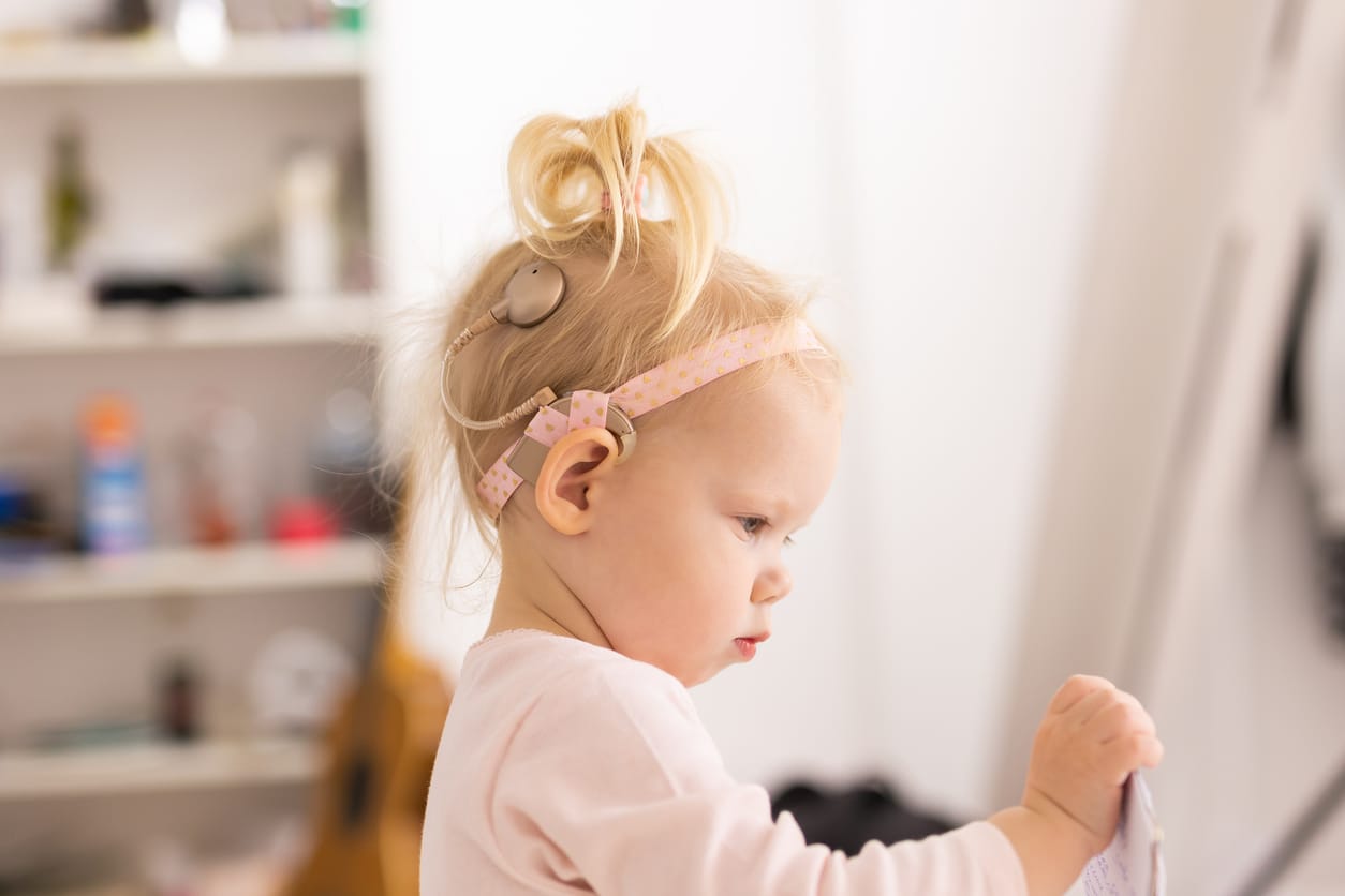 Young girl with hearing aids holding paper