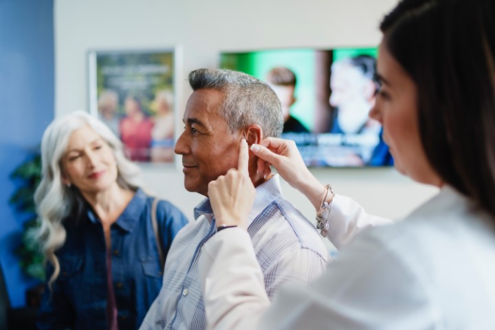 audiologist fitting hearing aid in ear