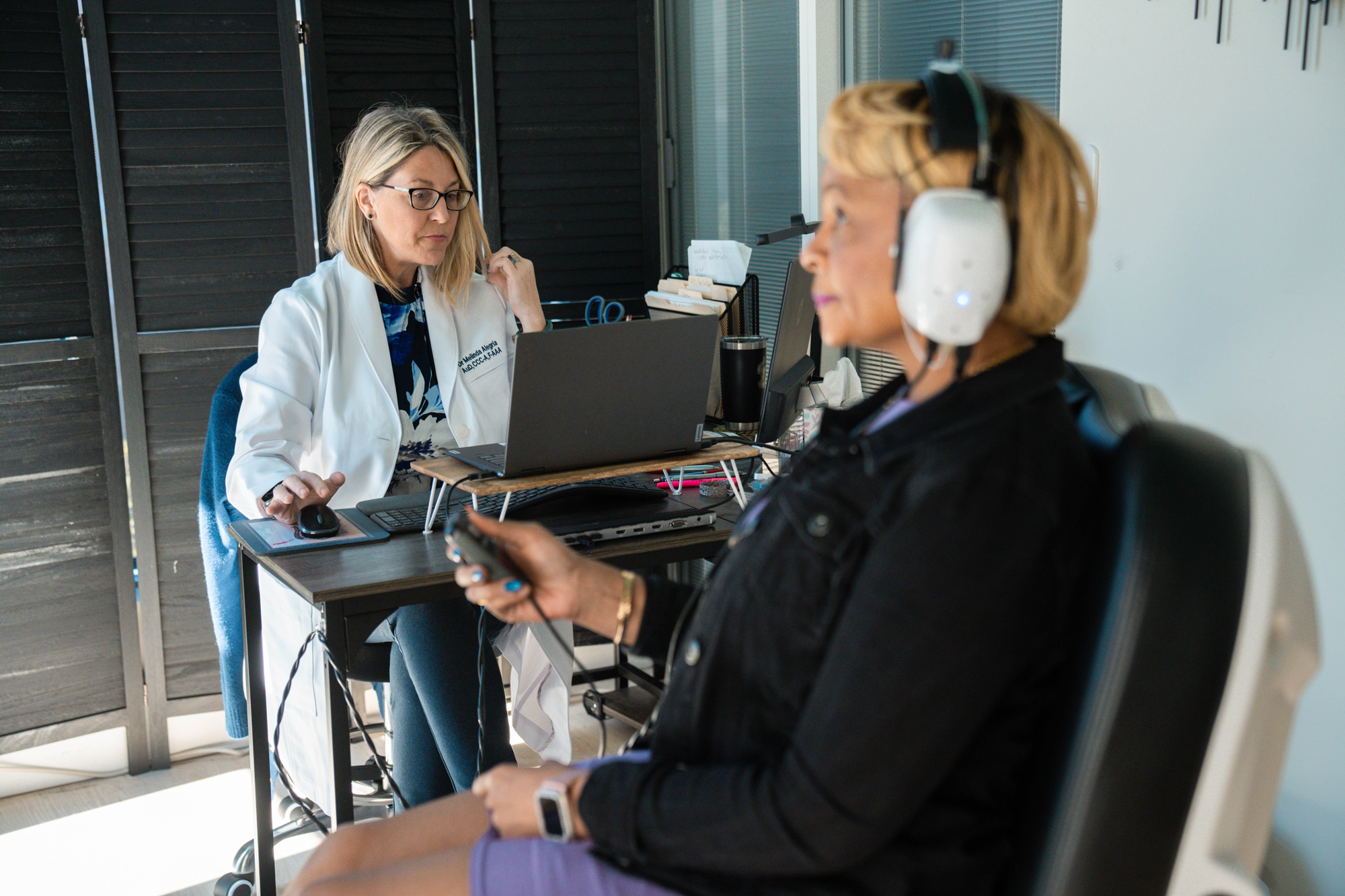 Dr Alegria performing hearing test in office with woman patient