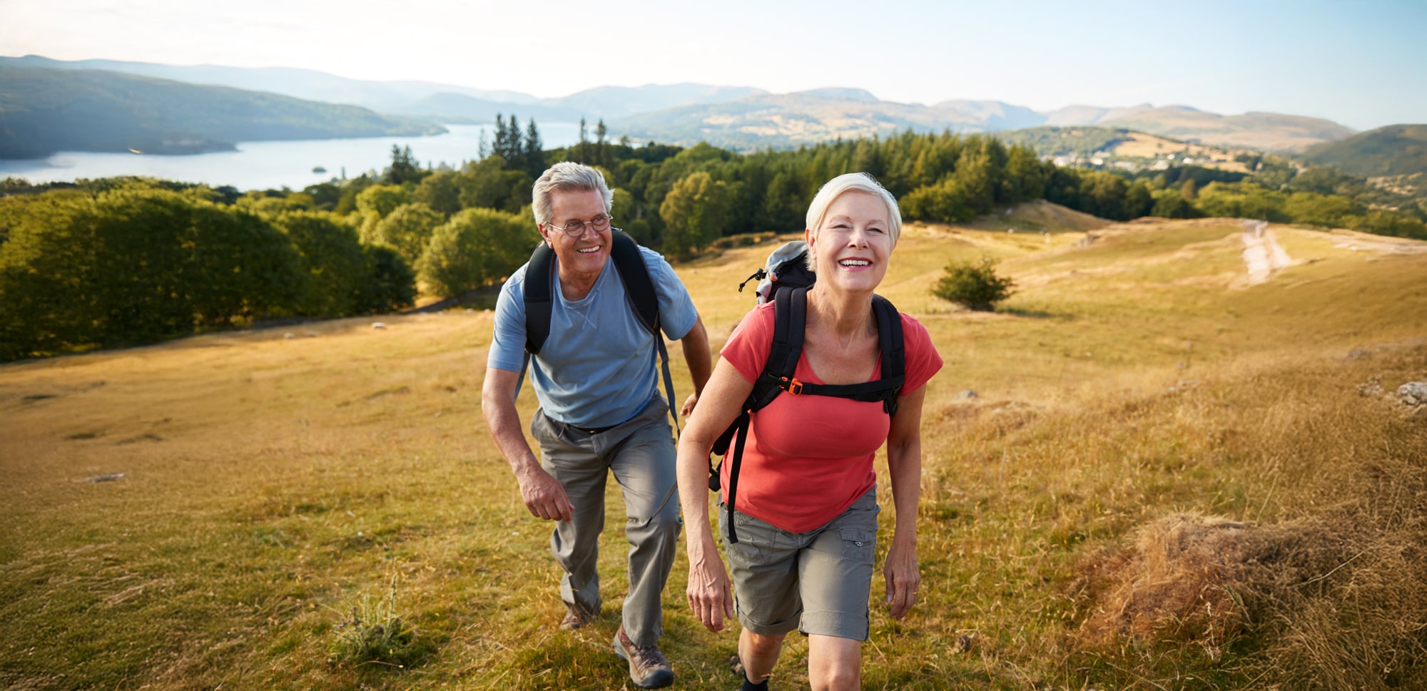 hero banner mature couple hiking alongside hill min