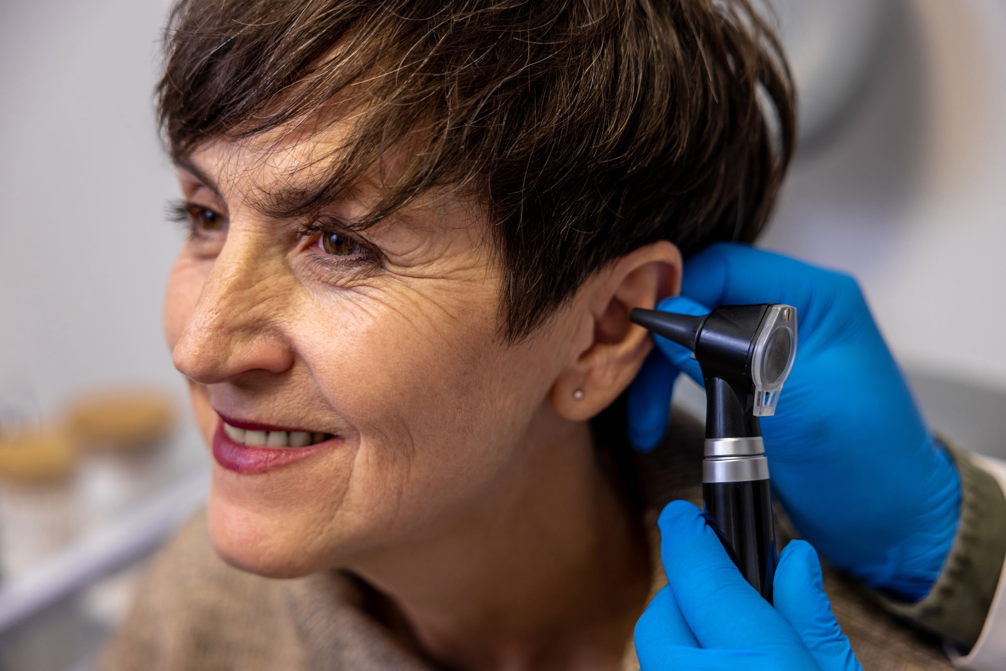 hearing care provider inspecting woman patient ear with otoscope