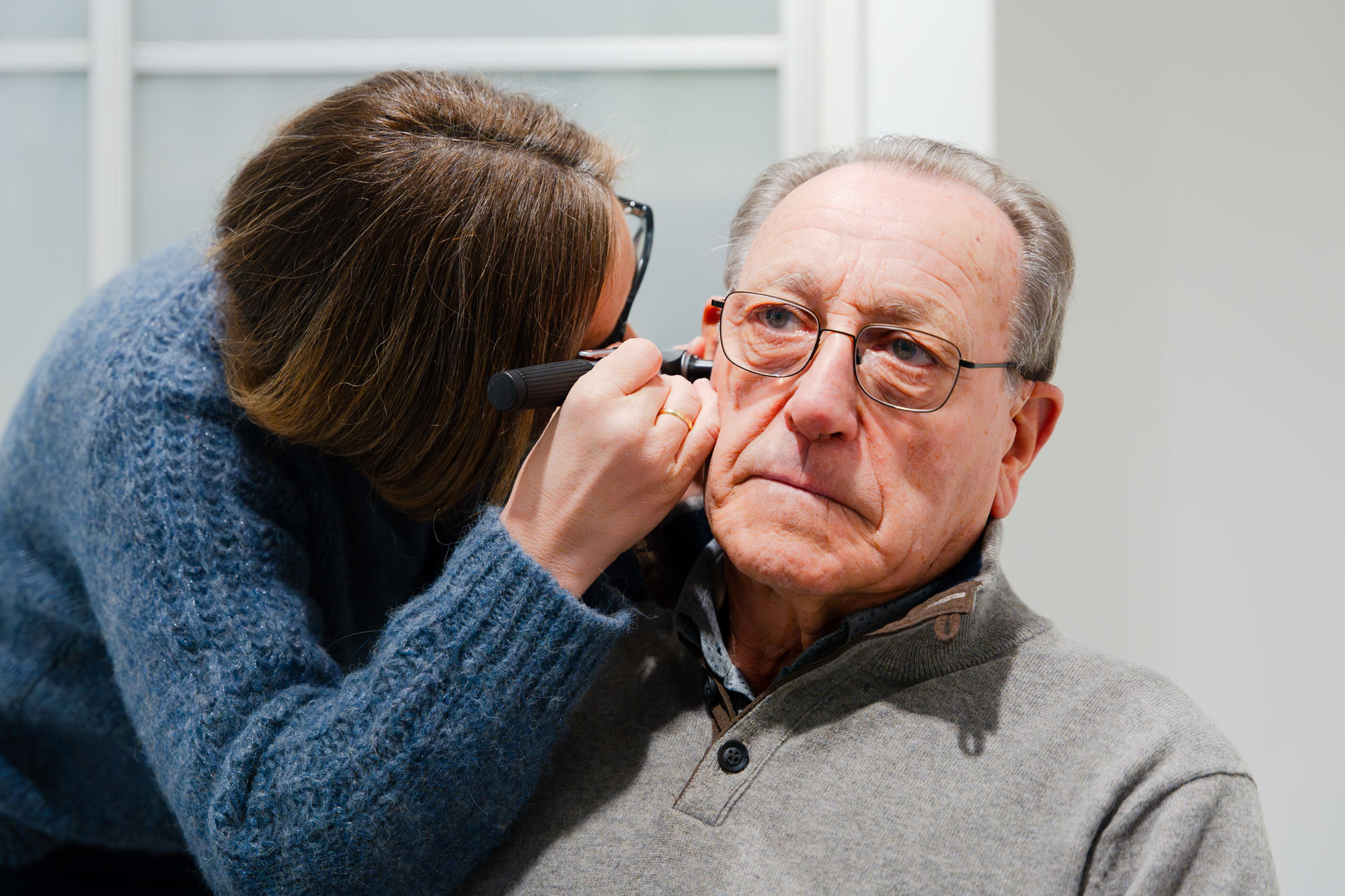 hearing care provider inspecting patient ear with otoscope