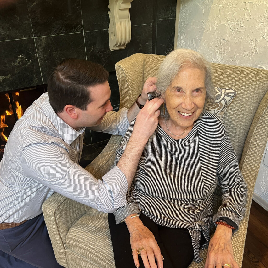 Dr Craig Heffron inspecting patient ear with otoscope at home