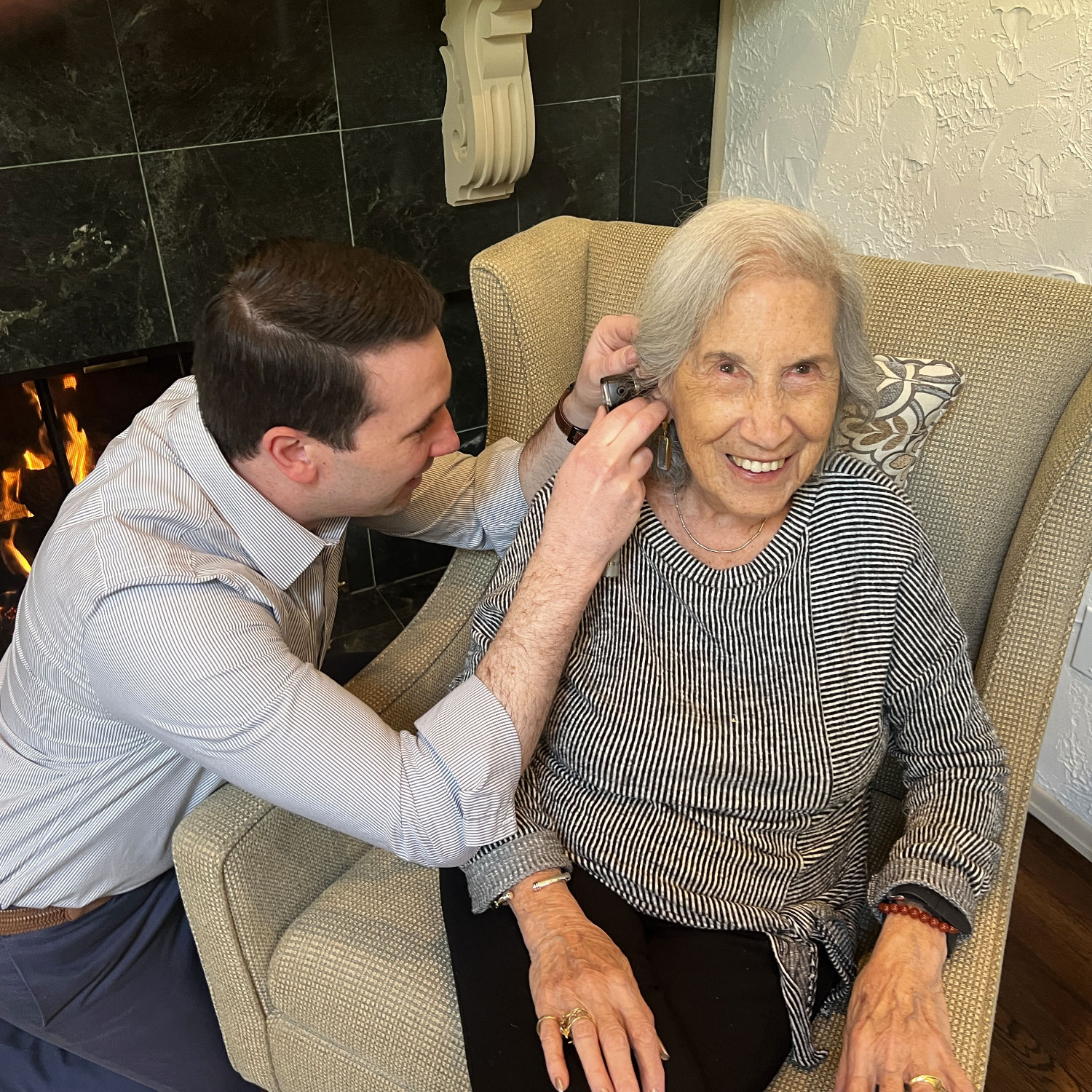 Dr Craig Heffron inspecting patient ear with otoscope at home