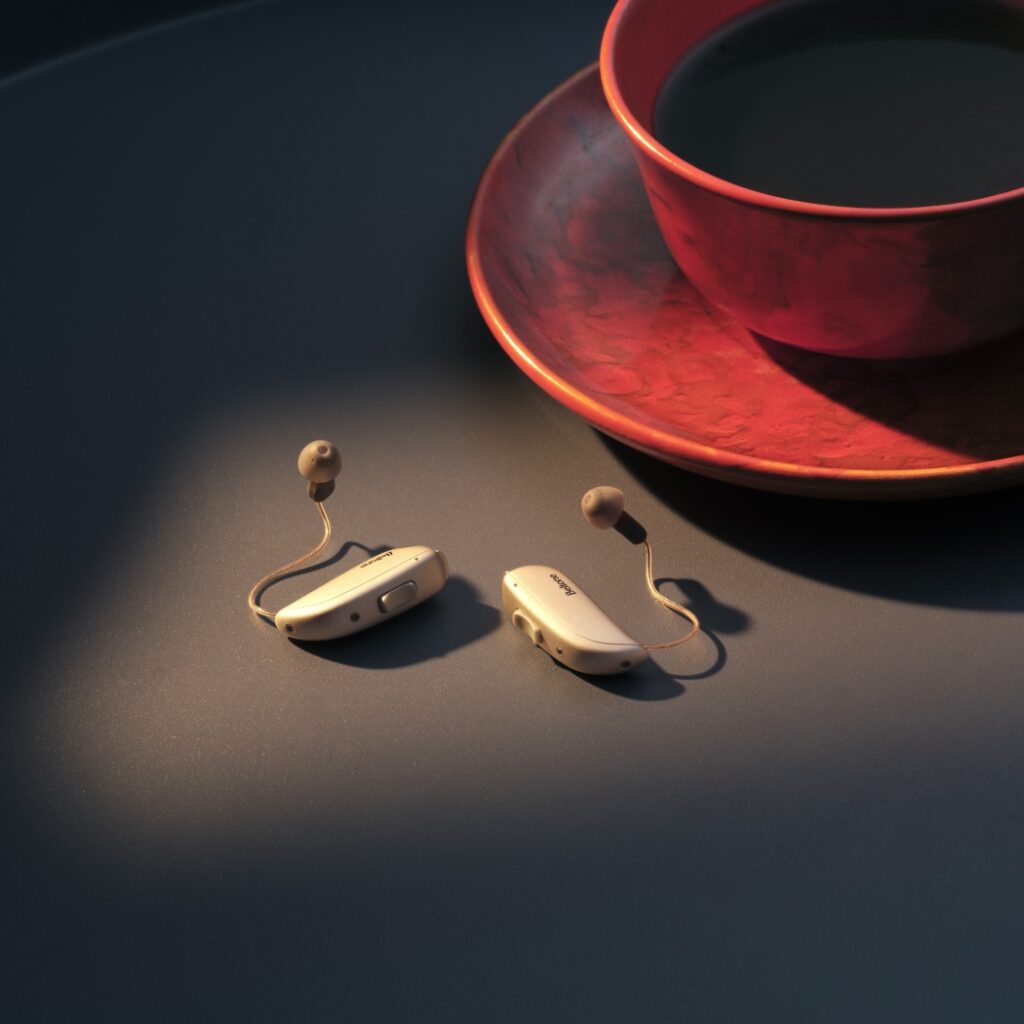 Beltone Envision RIE 64 hearing aids on table by coffee mug