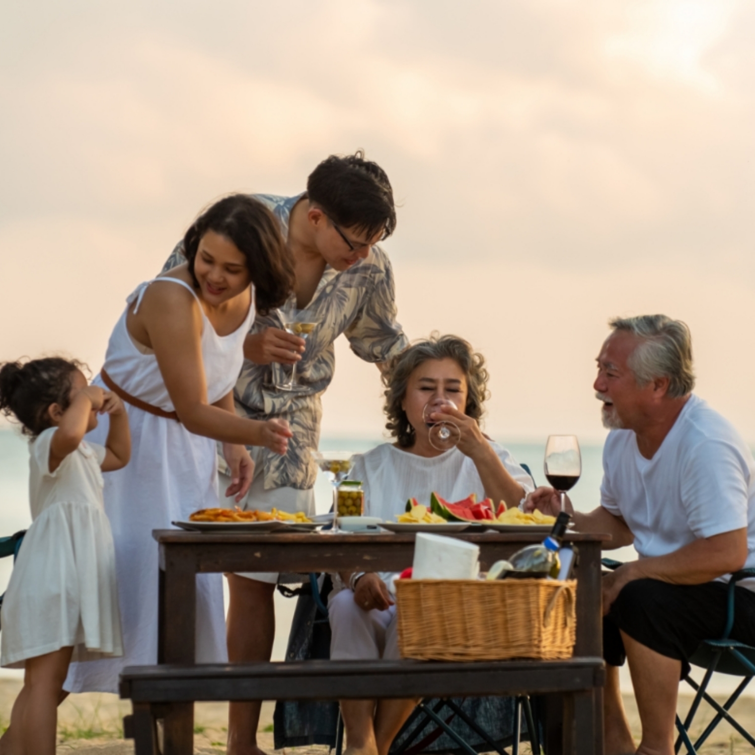 generation family little girl with parents and grandparents relax and enjoy with dinner party and dancing together on the beach