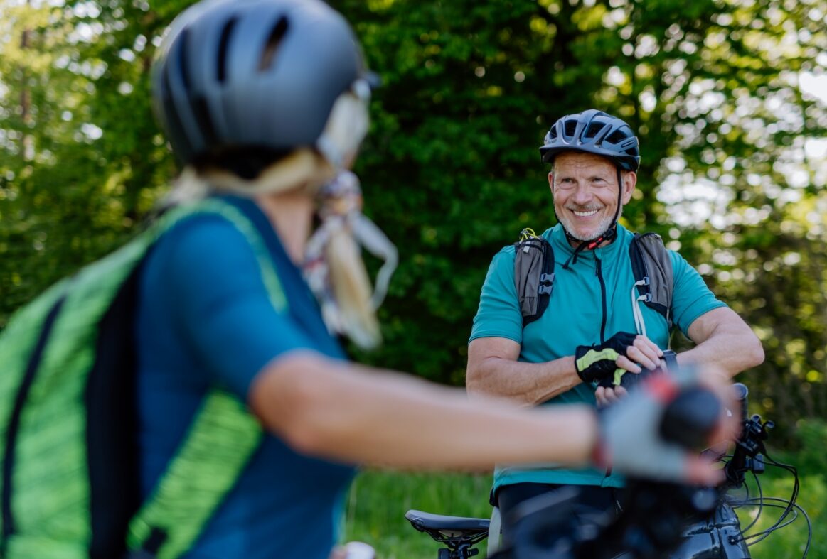 active senior couple riding bicycles at summer park
