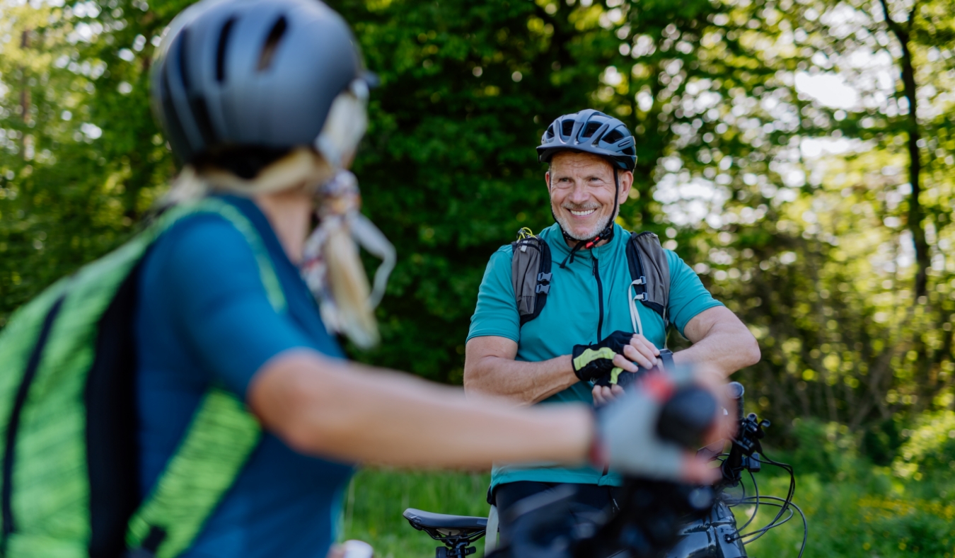 active senior couple riding bicycles at summer park