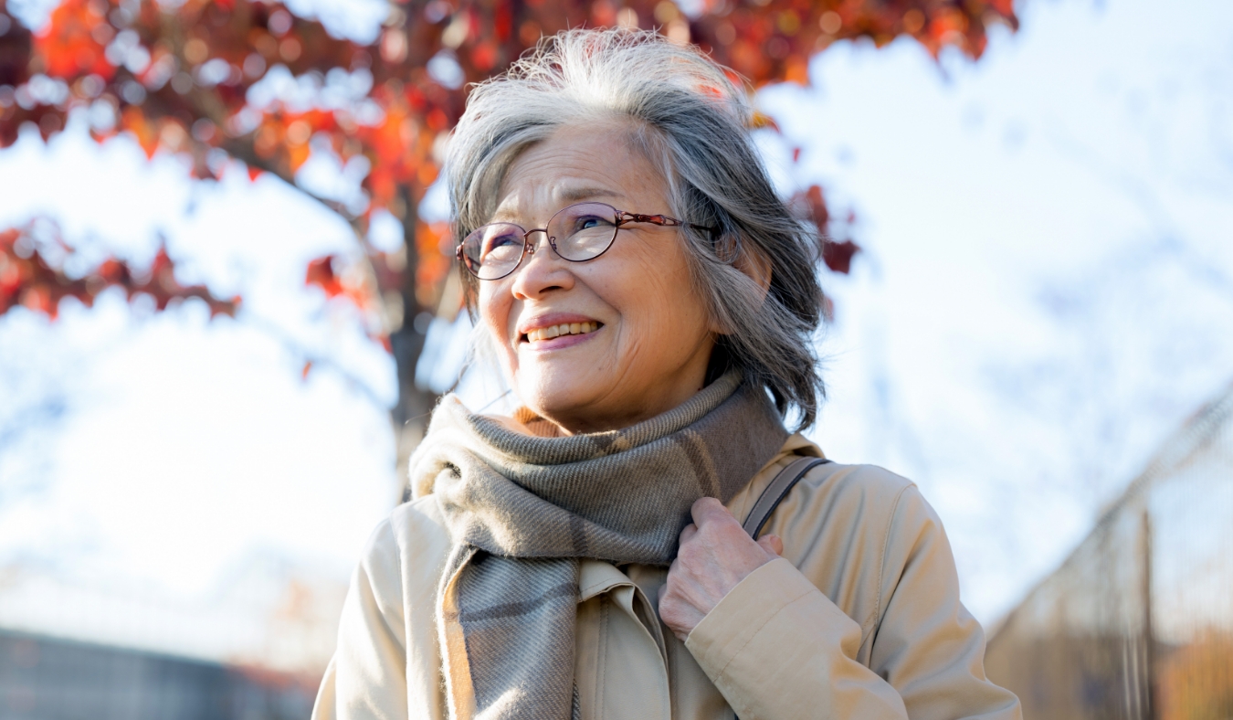senior asian woman smliling with red leaves behind