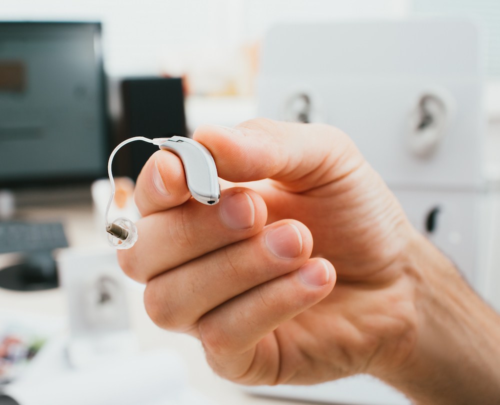 hand holding a light grey bte hearing aid