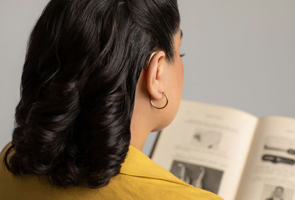 gn group woman wearing hearing aid while reading