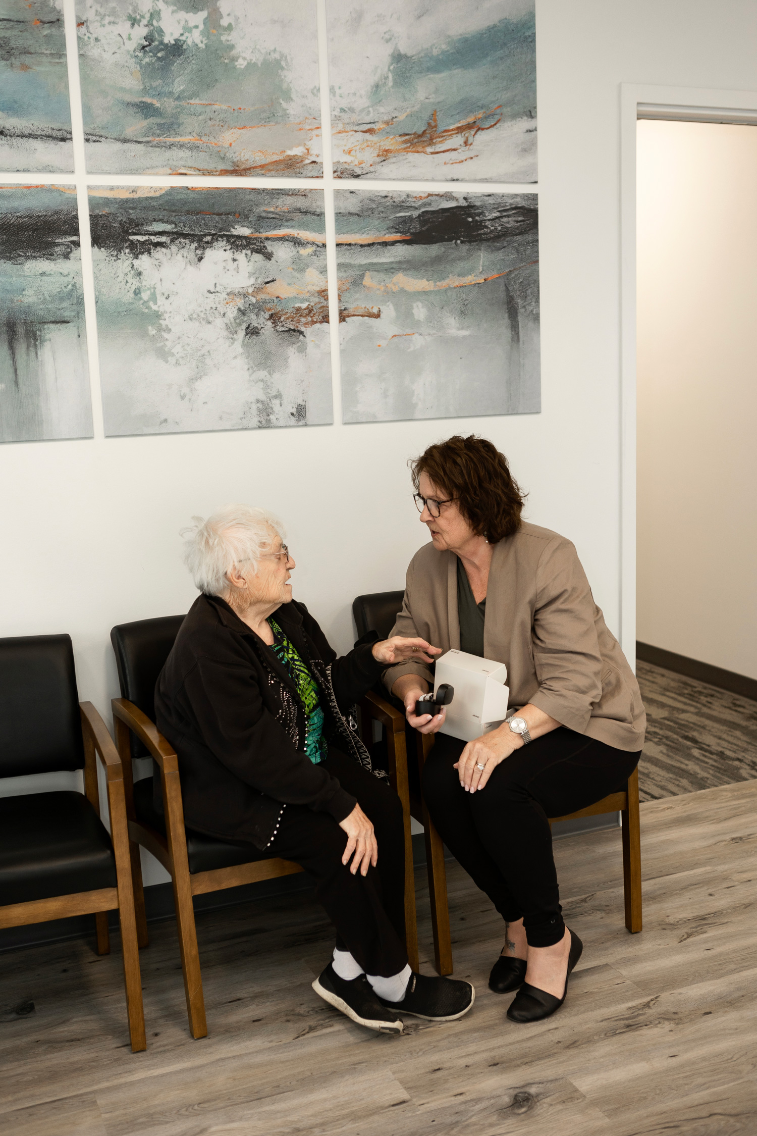 acoustic audiology kim helping a senior woman in waiting area