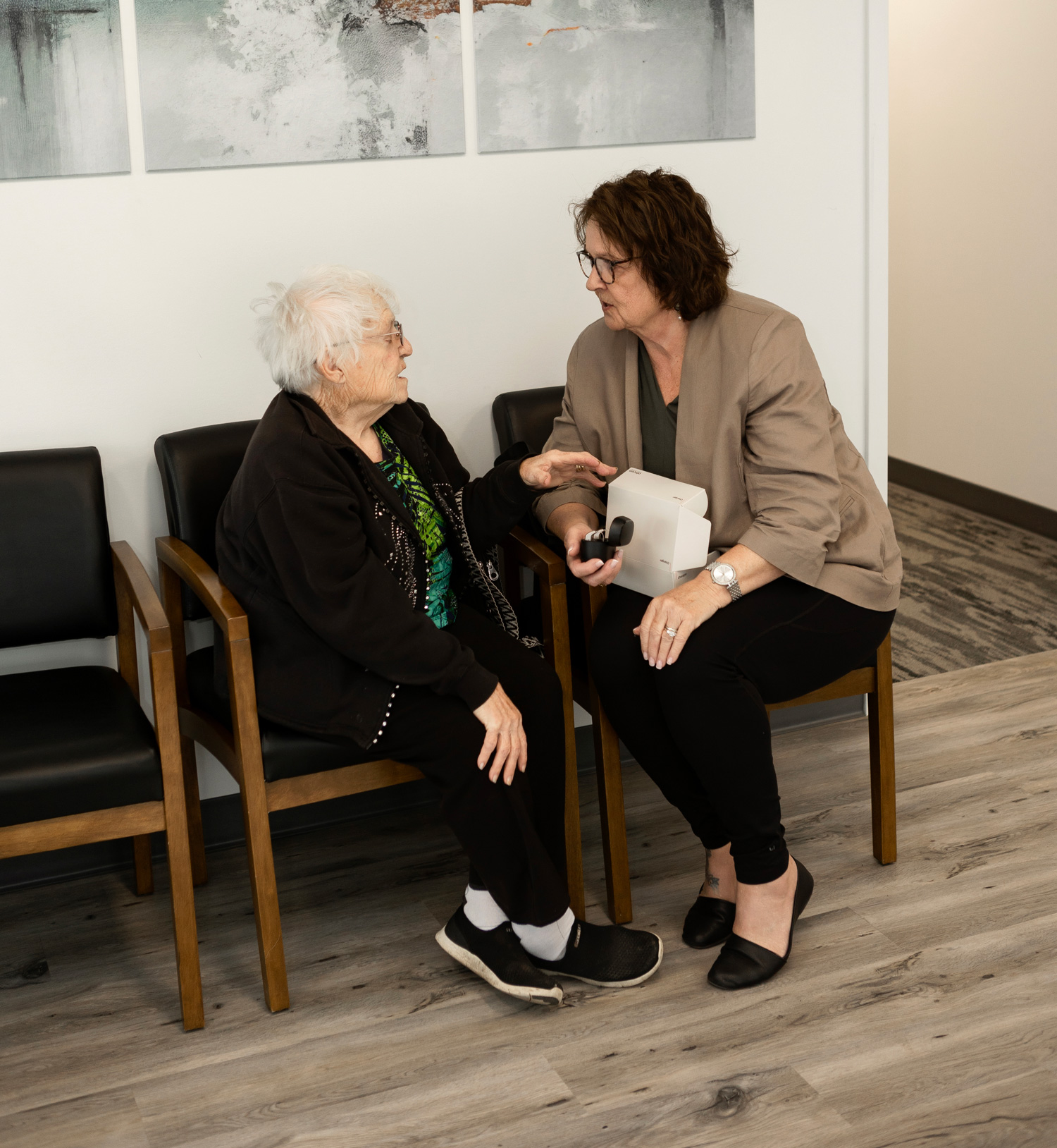 kim helping a senior woman with her hearing aids