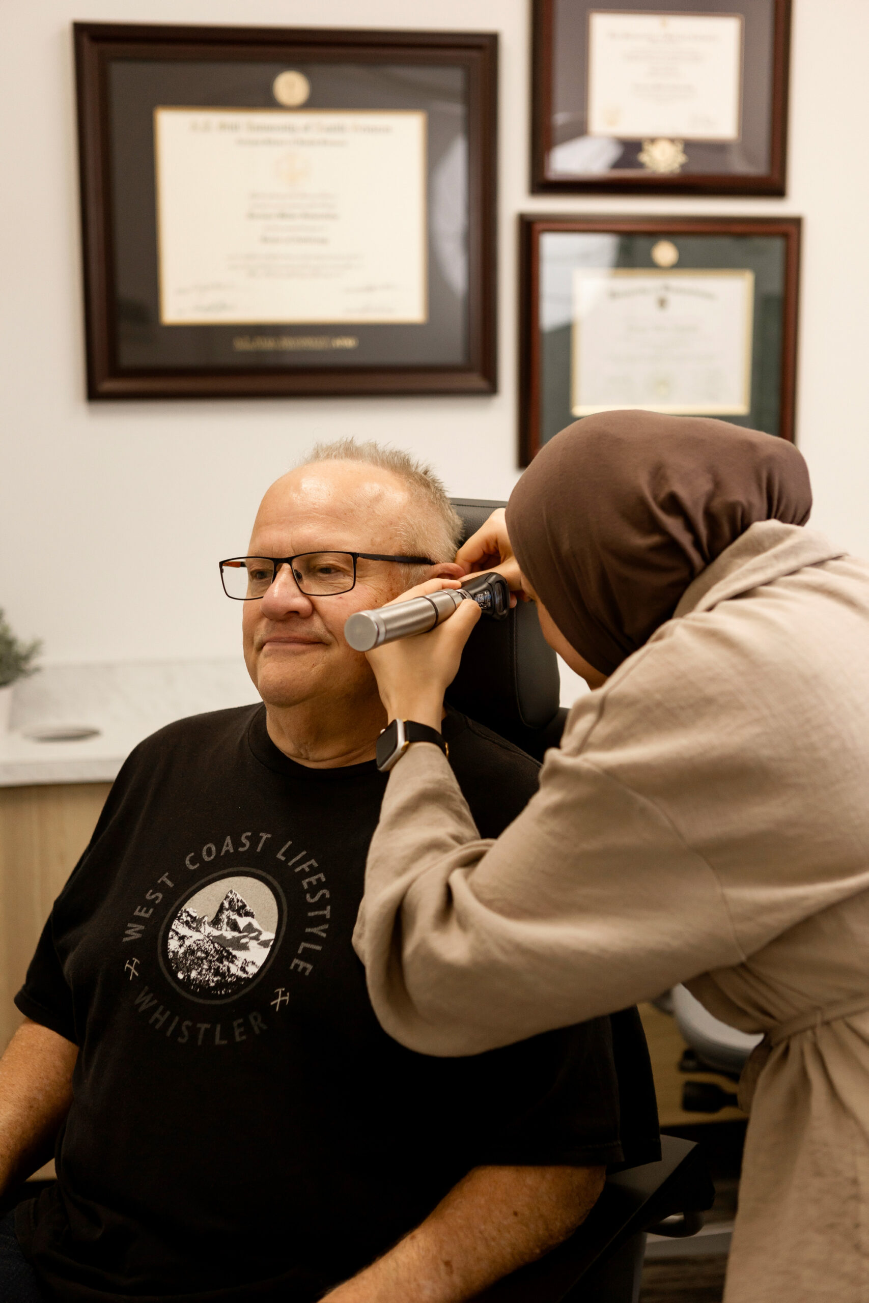 Maysem Elfurjani looking into mans ear with otoscope