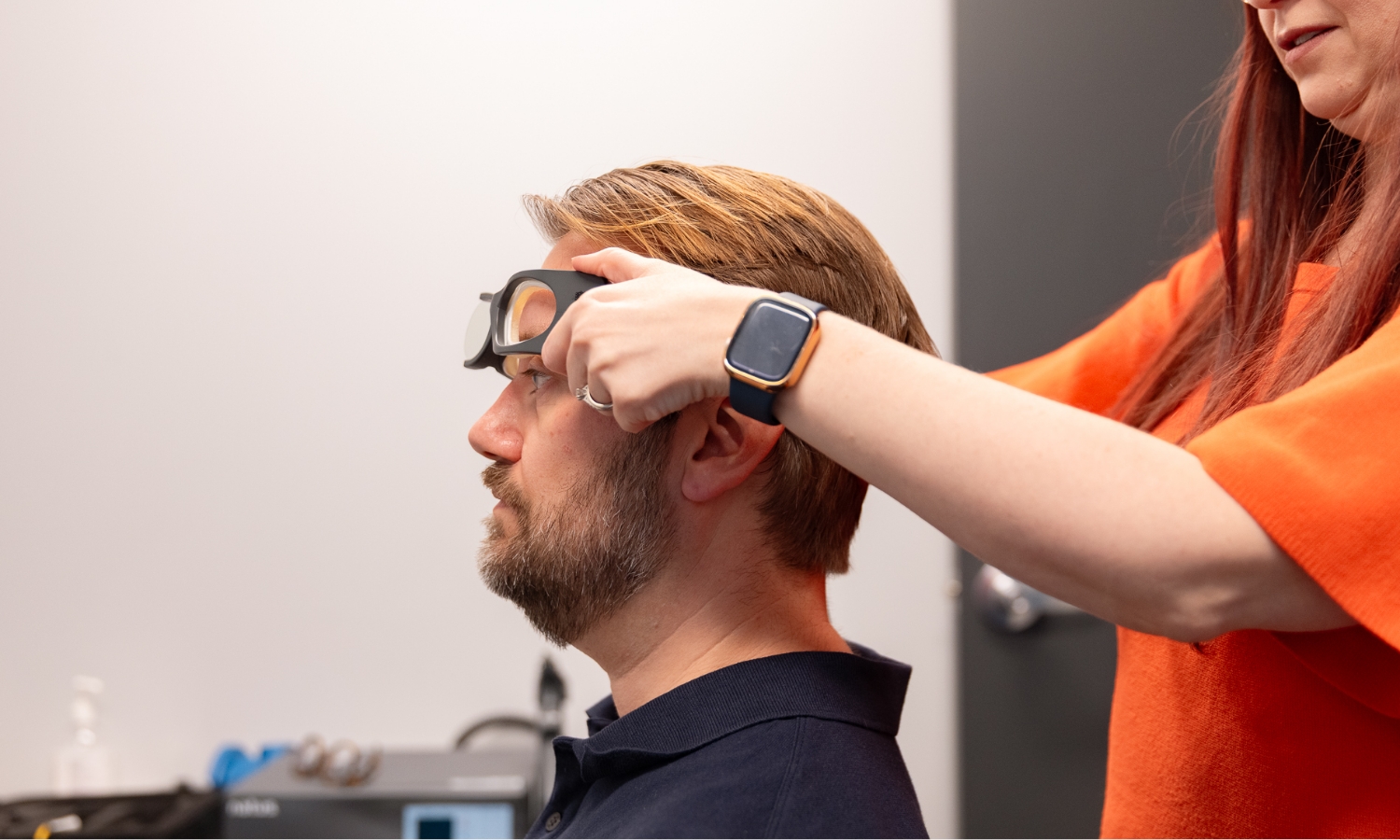 Technician fitting goggles on seated person for VNG balance and vestibular testing.
