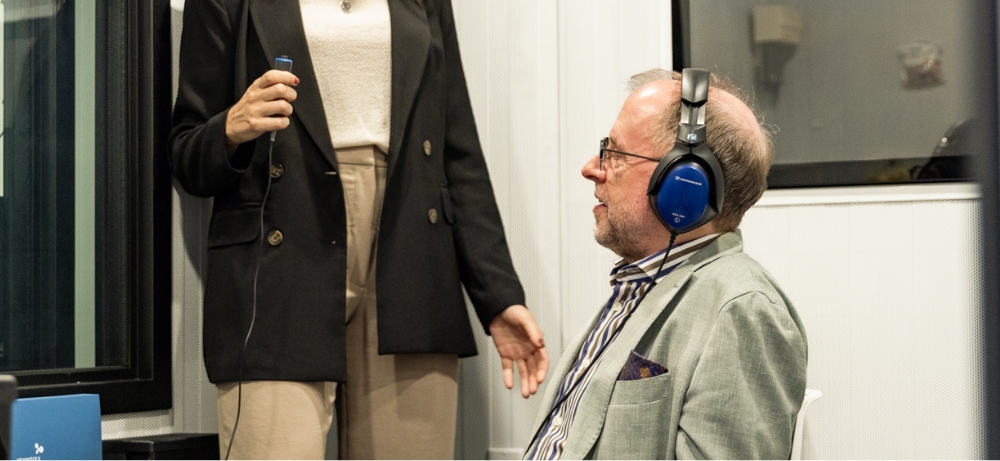 real value research Person wearing headphones seated while another person holds a device, likely during a hearing test.