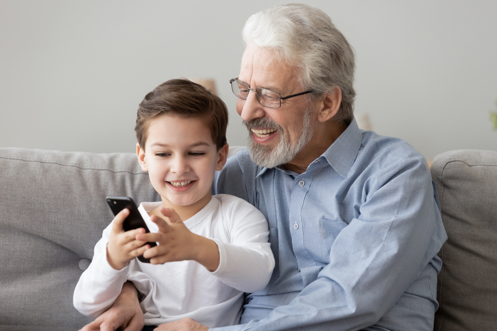 Happy,Senior,Grandfather,And,Cute,Small,Grandson,Using,Smart,Phone
