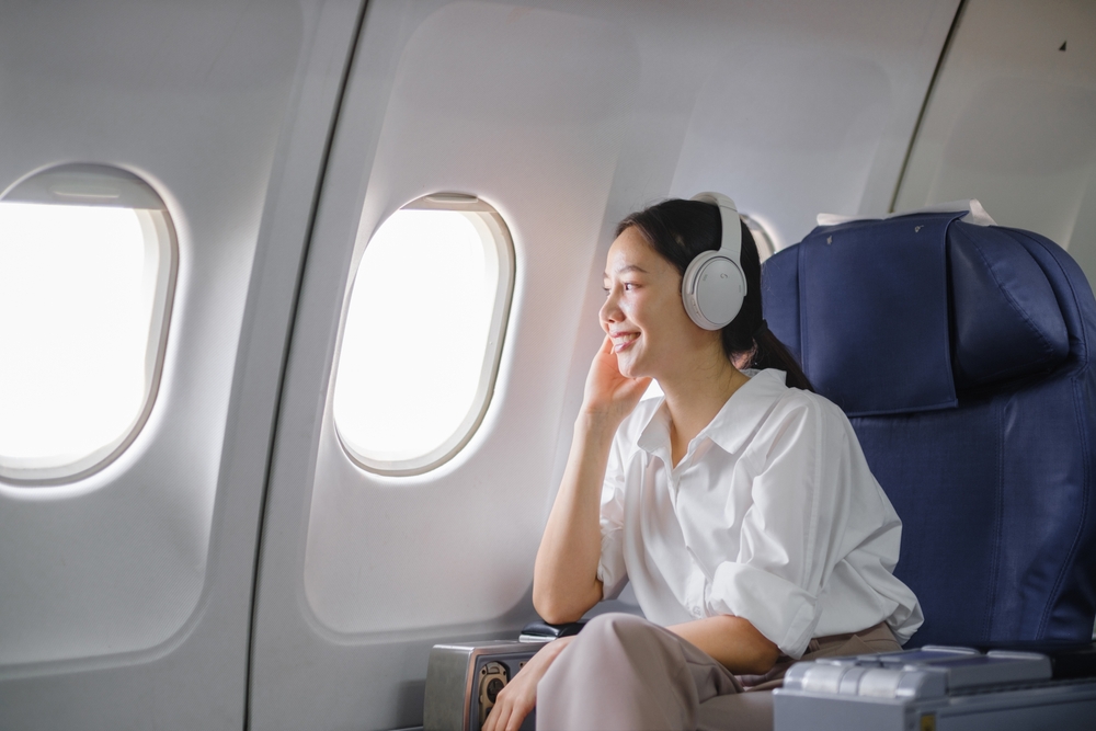 Asian,Woman,Sitting,And,Using,A,Smartphone,In,An,Airplane