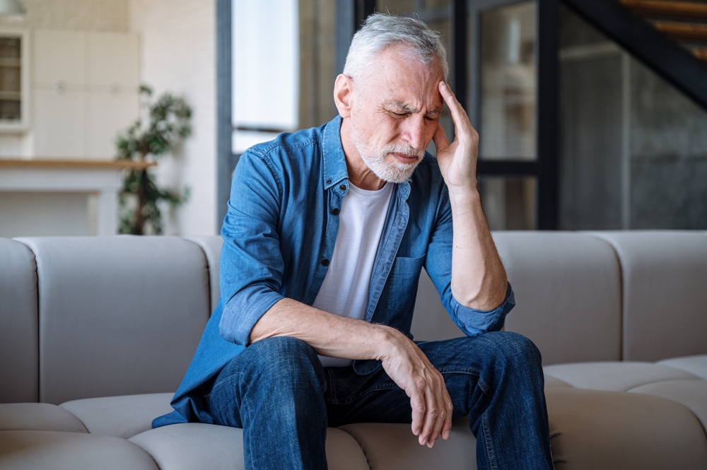Mature,Man,Sitting,On,Sofa,,Feeling,Headache,,Dizzy,Or,Problems