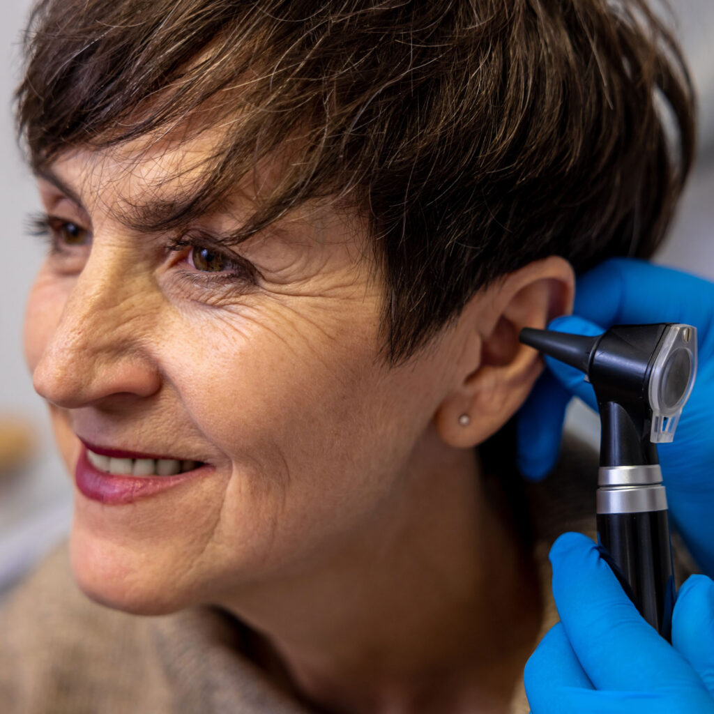mature woman being looked at with otoscope by professional