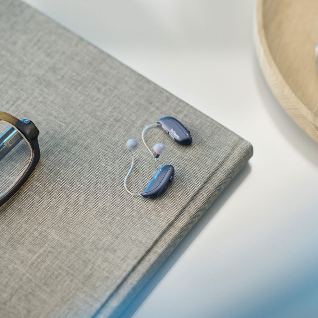 ReSound Vivia lifestyle hearing aids on book lifestyle graphite