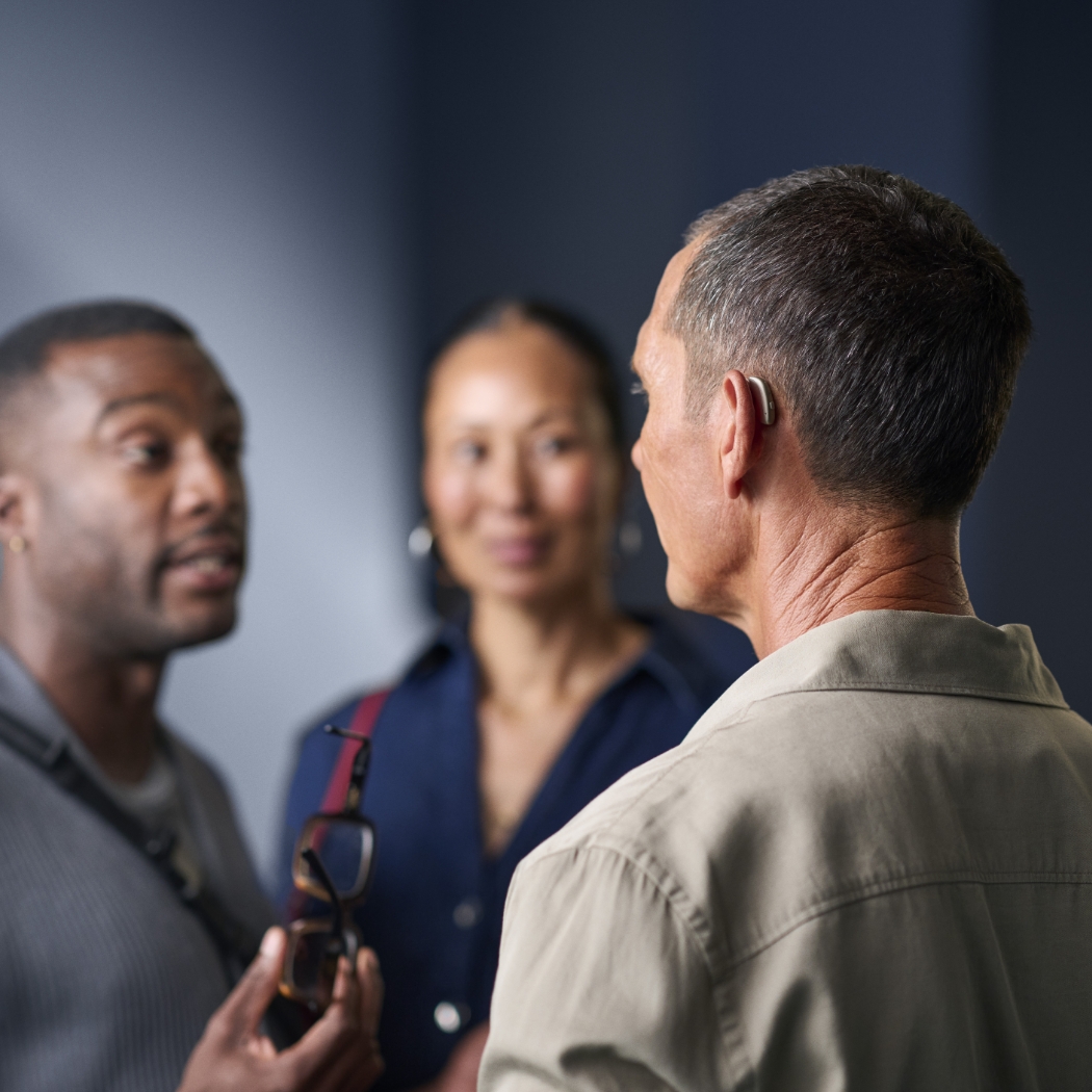 ReSound Savi lifestyle mature man with hearing aids talking in small group