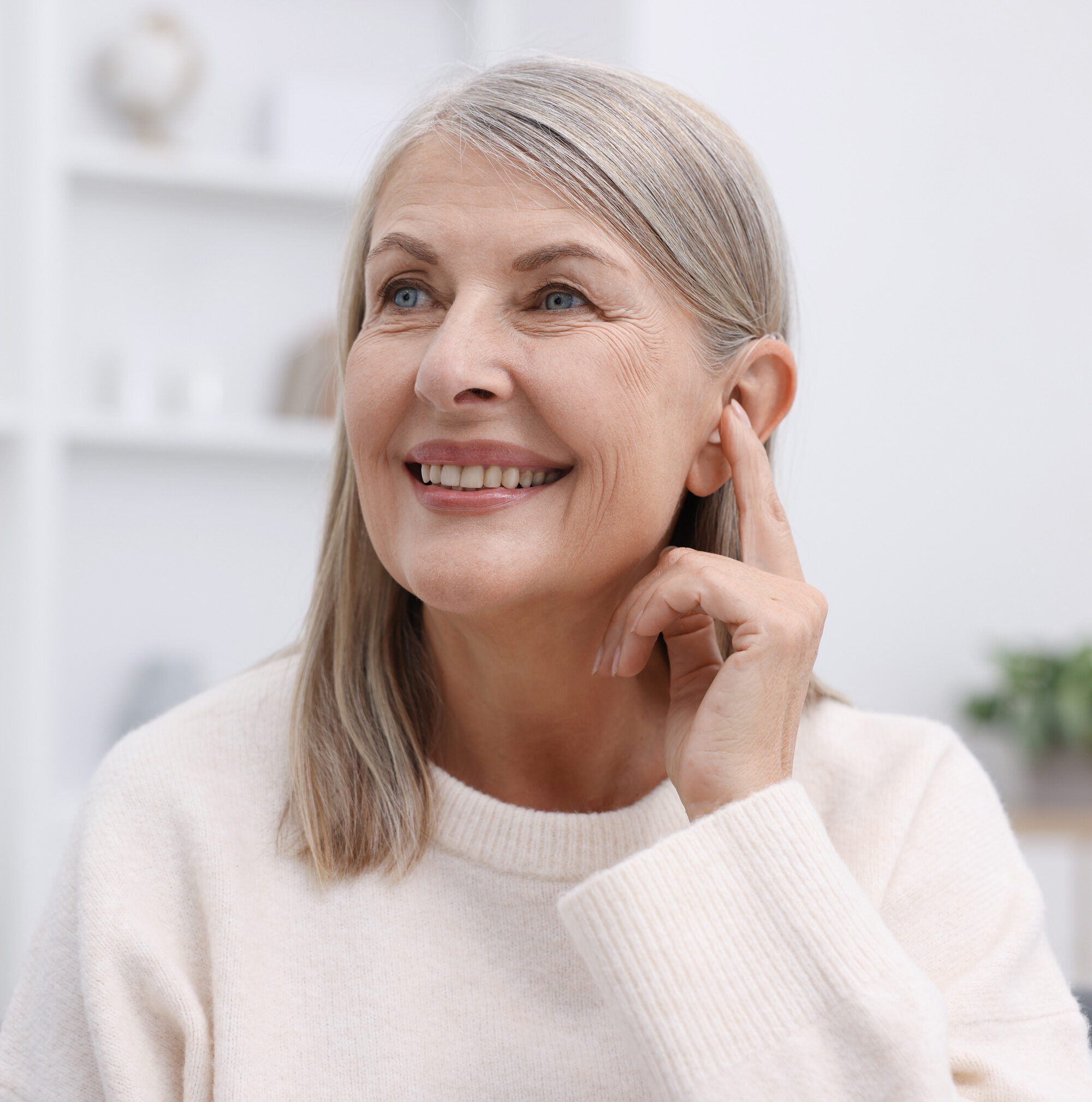 senior woman holding finger to ear during hearing aid fitting