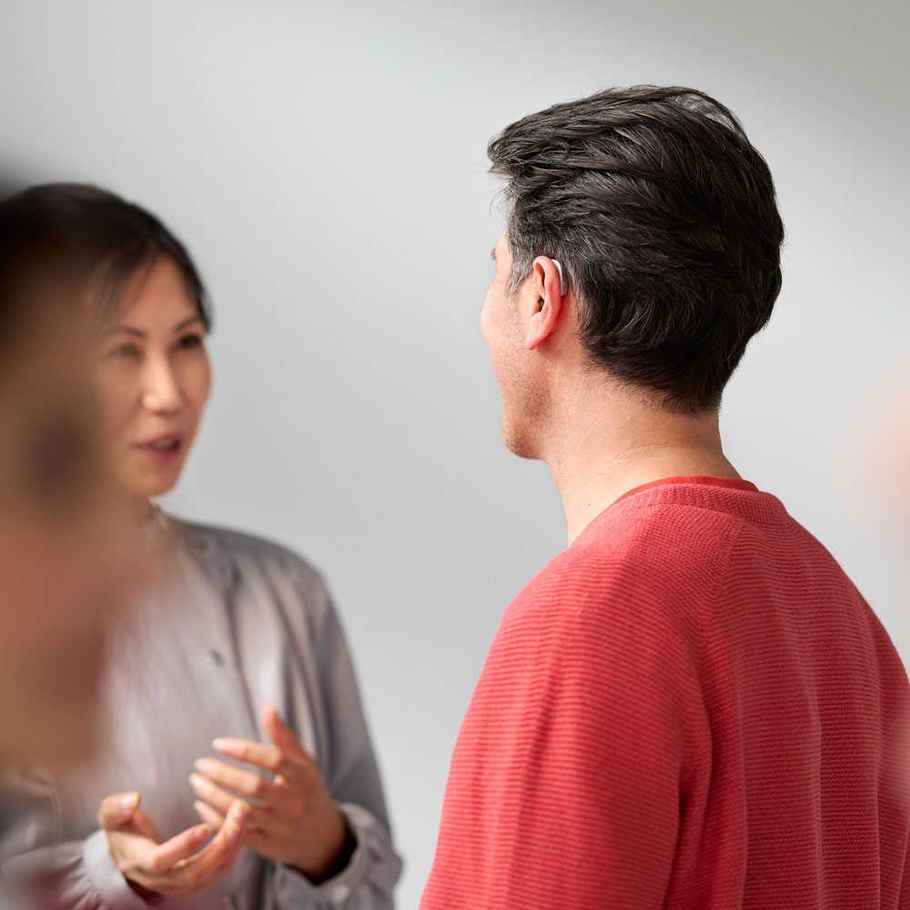 resound sensia lifestyle man wearing rie silver hearing aid talking to woman