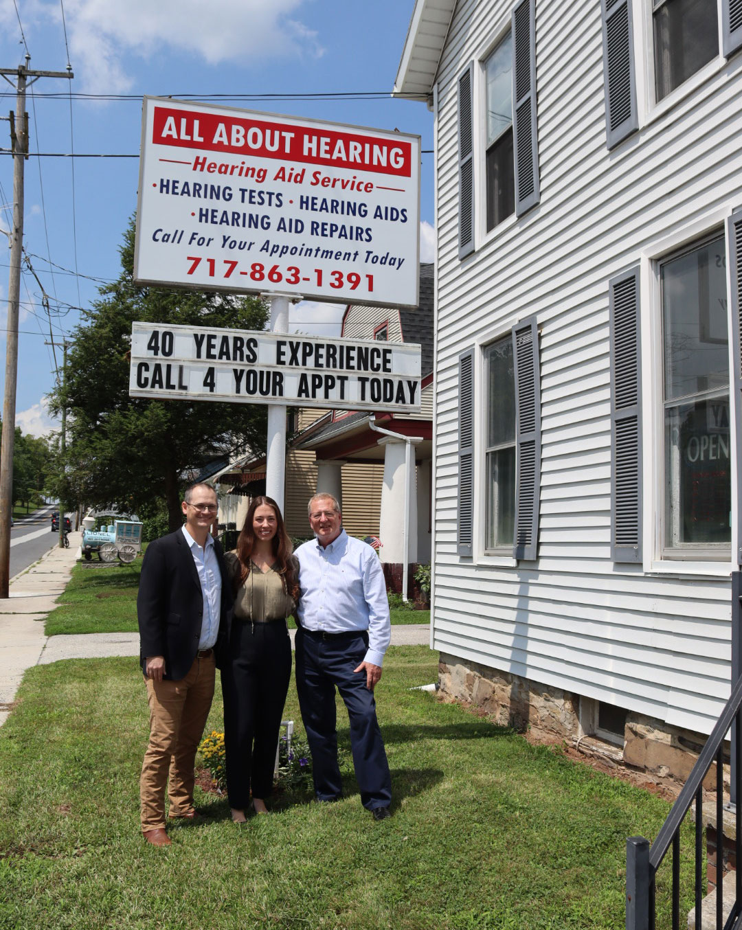 All About Hearing staff standing outside by sign