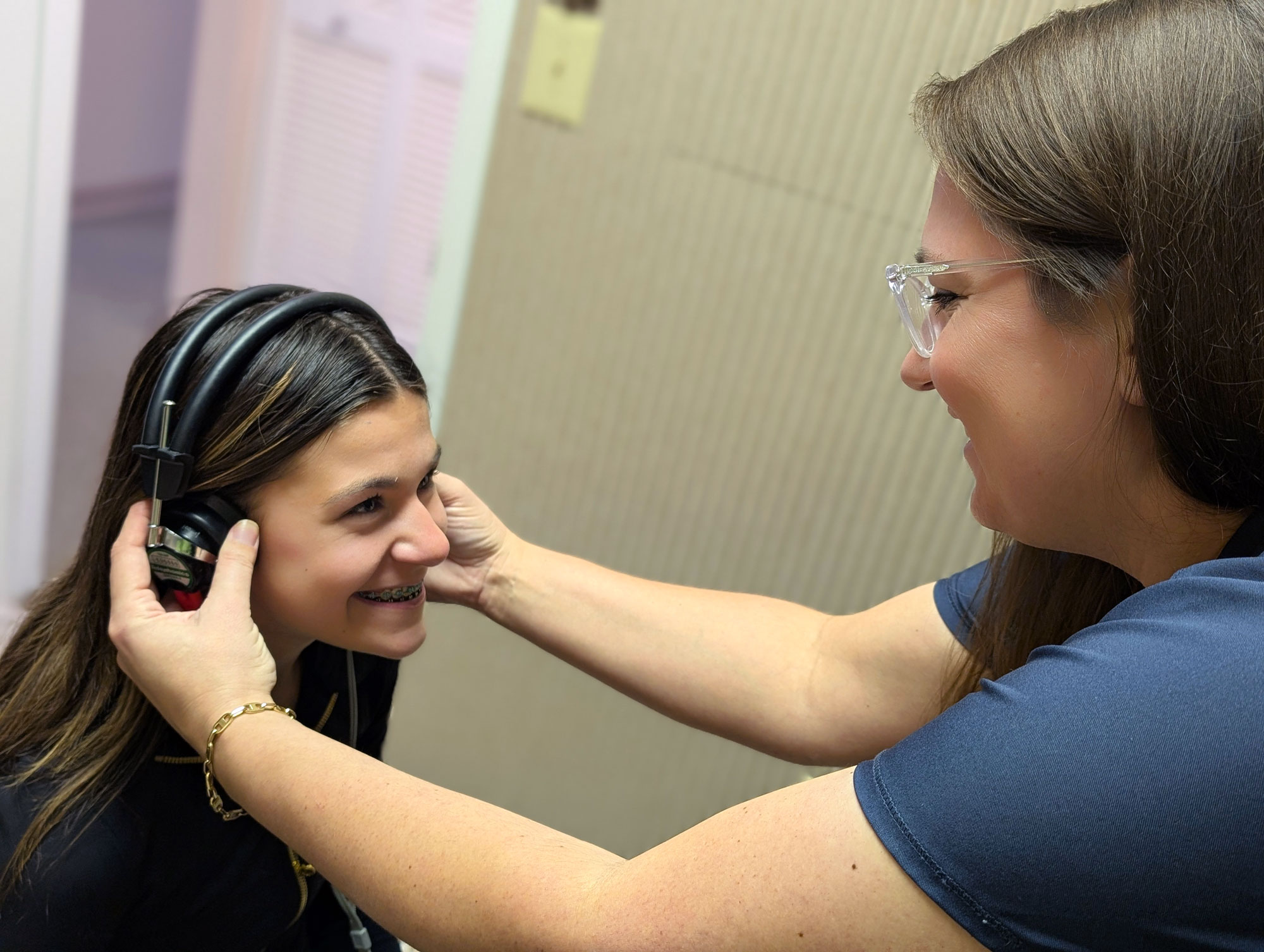 Kelli Shivers Beswick Au D putting headset on patient in soundbooth