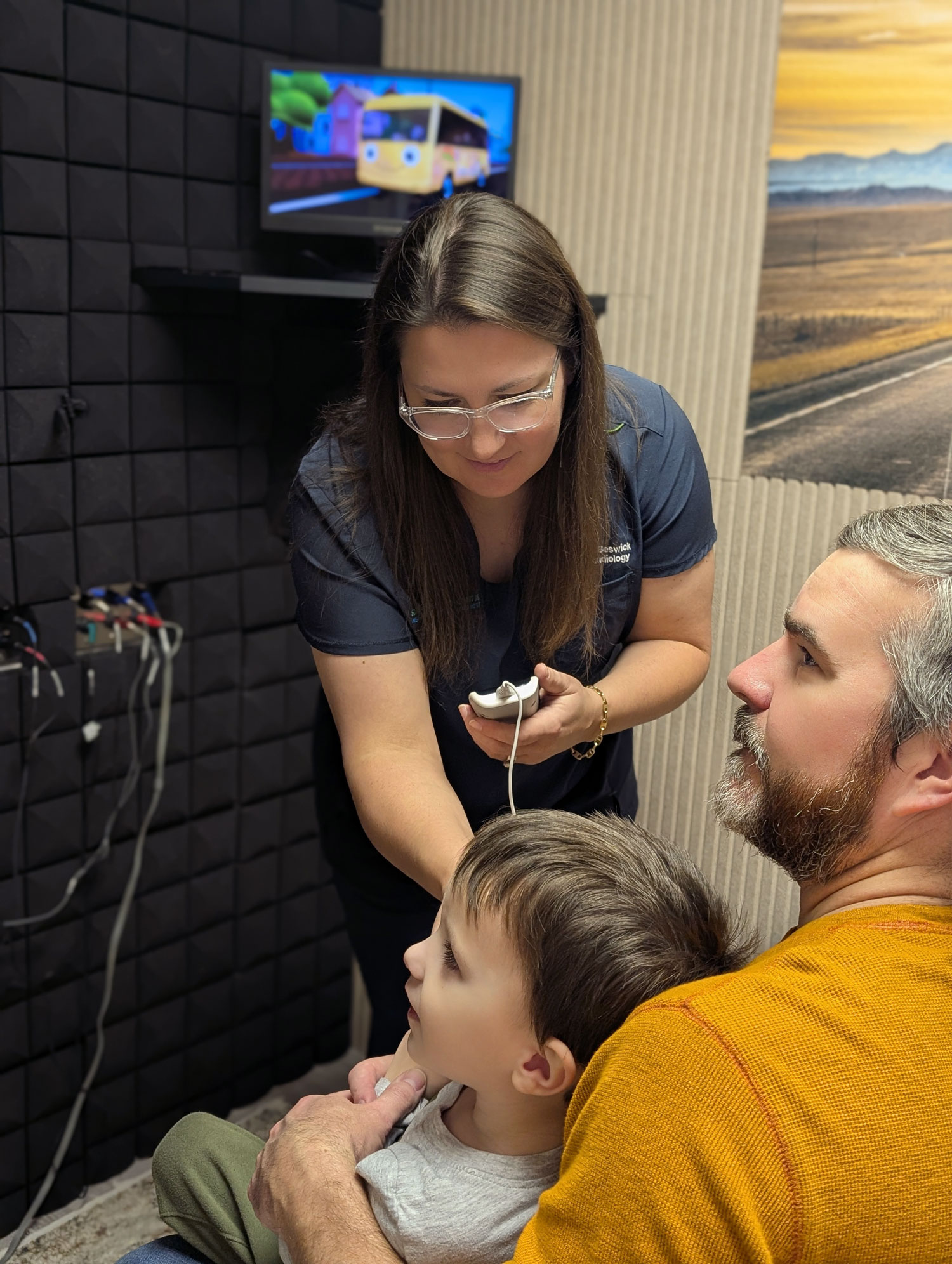 kelli shivers performing hearing test on child whilte in dads lap