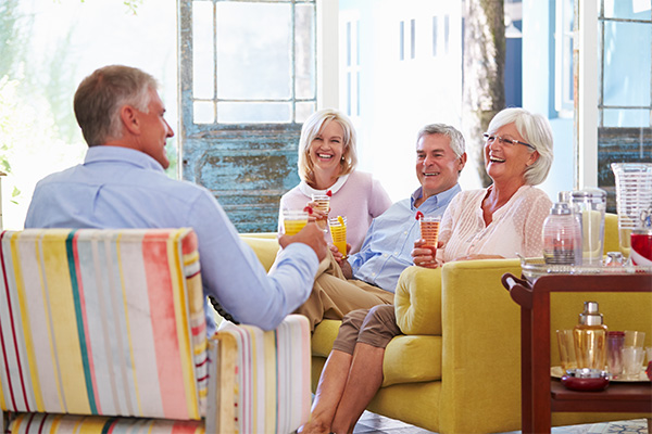 two couples sitting on love seats eating lunch together