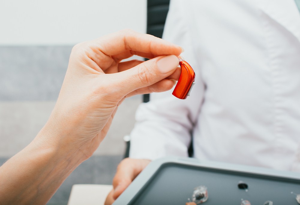 hand holding a red bte hearing aid device optimized