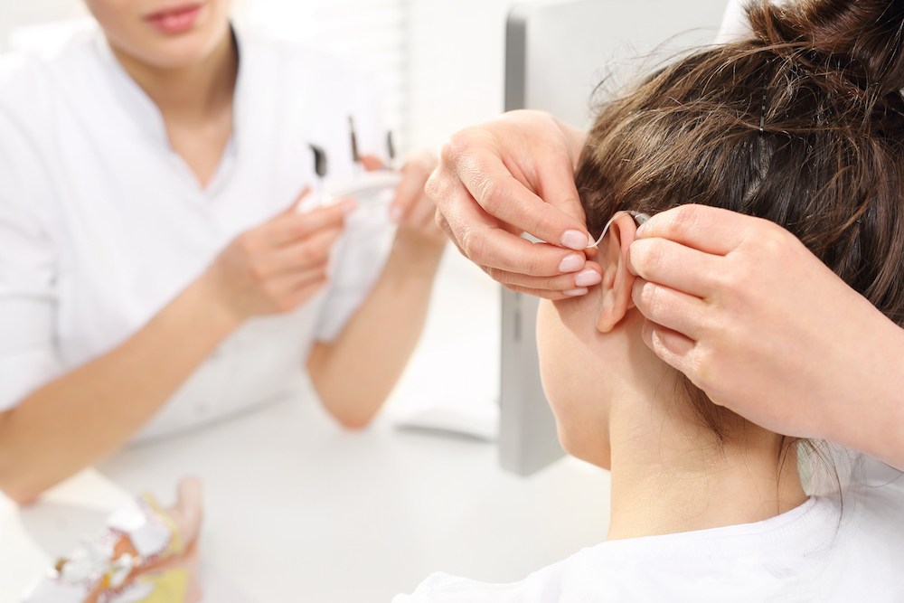 hearing specialist fitting patient with hearing aid devices optimized