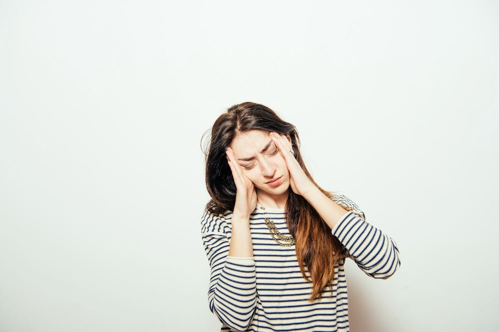woman holding hands to head with scrunched face in distress