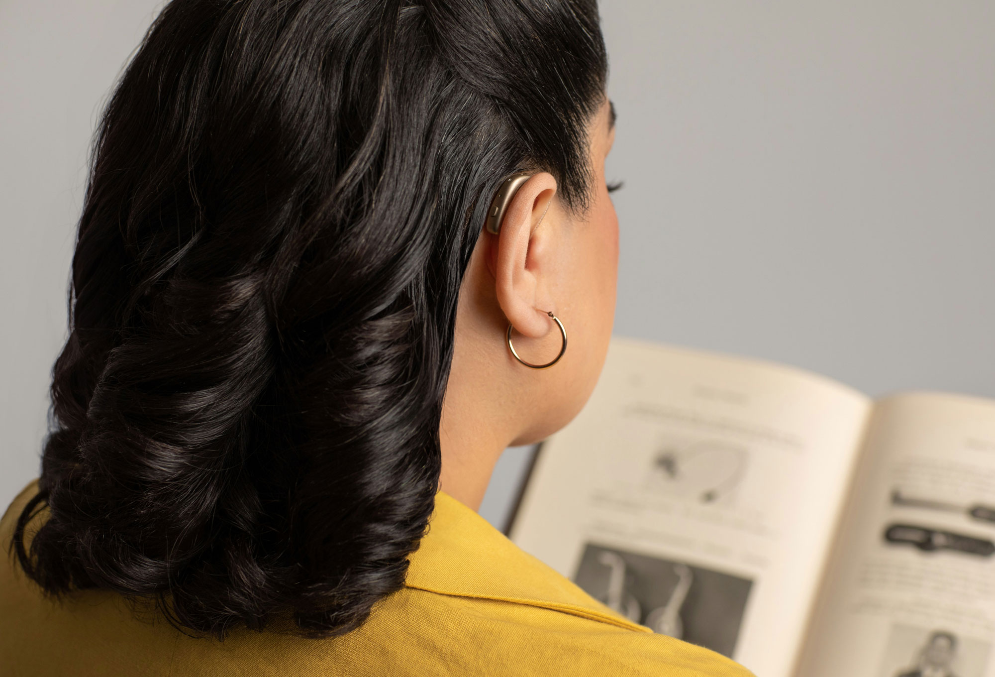 gn group woman wearing hearing aid while reading