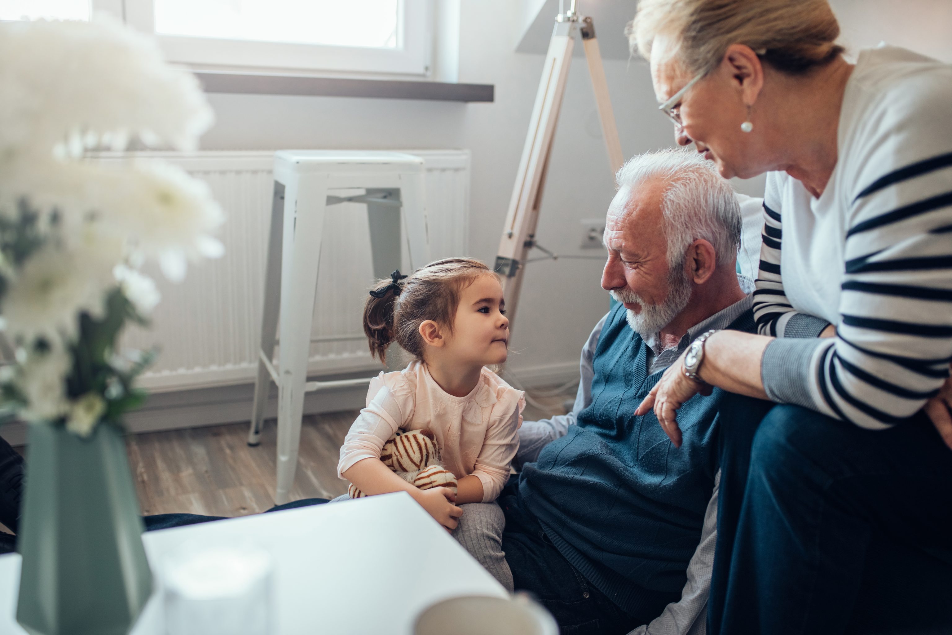 older man in chair talking with daughter and granddaughter