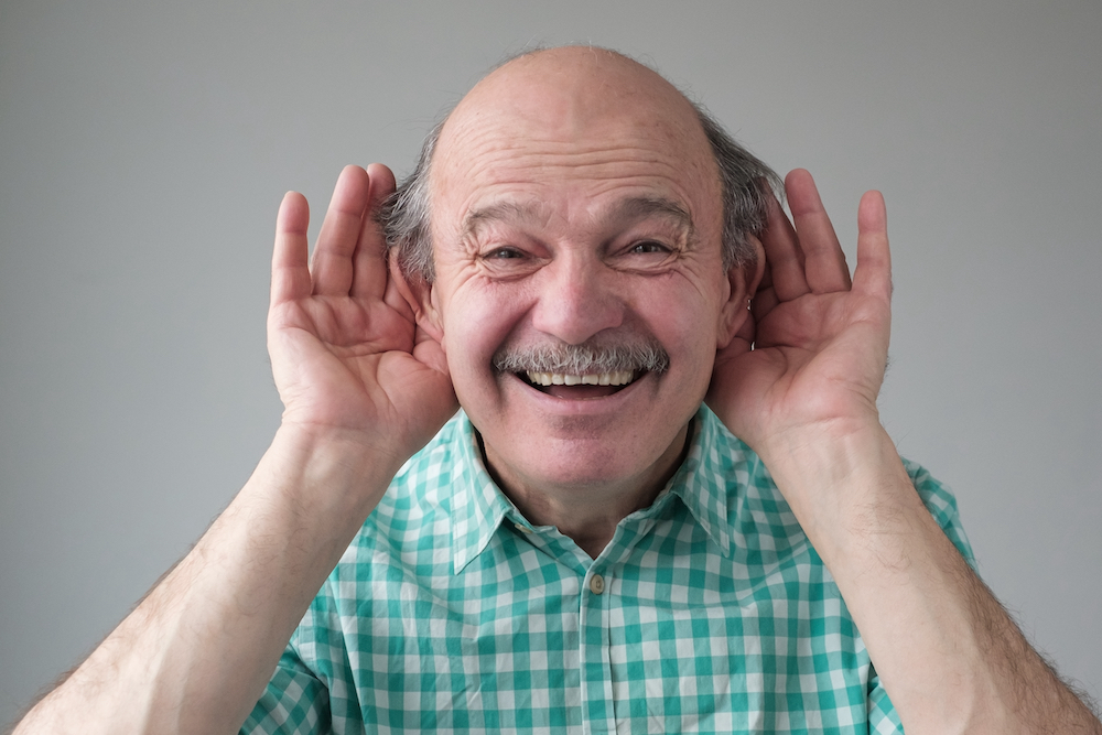 goofy looking man holding hand to ears