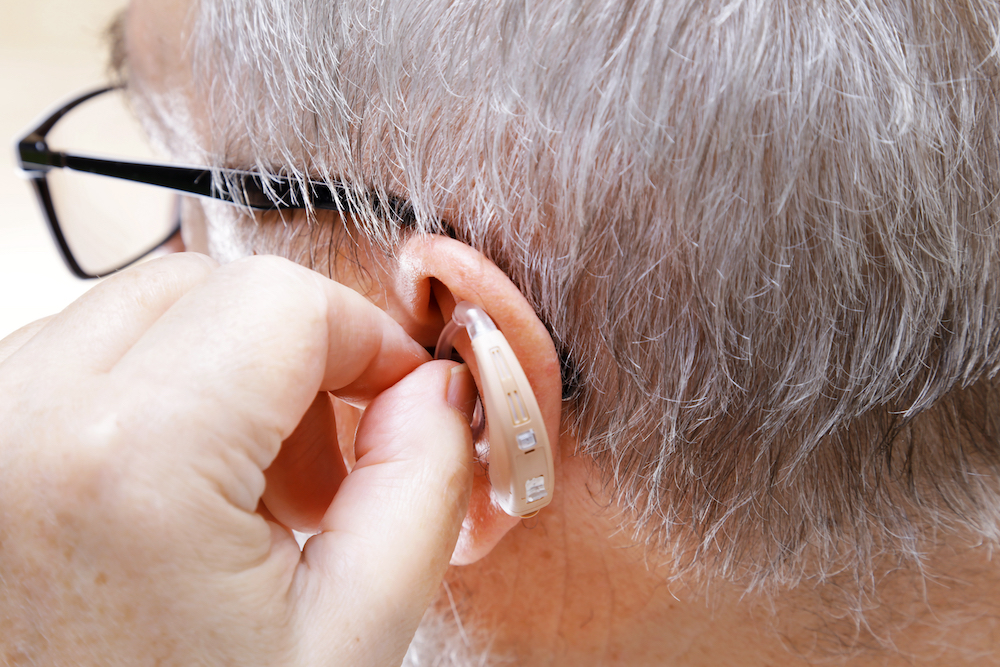 man inserting hearing aid into ears