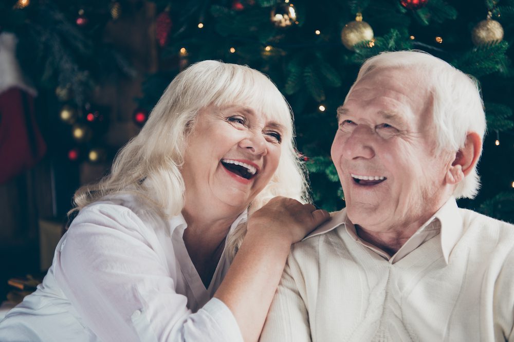husband and wife sitting in front of christmas tree