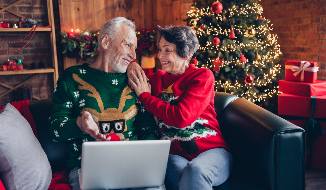 senior couple dressed for holidays using laptop