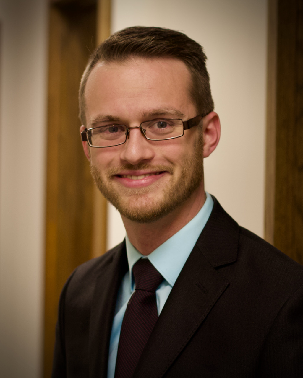 A person wearing glasses and a suitDescription automatically generated with medium confidence