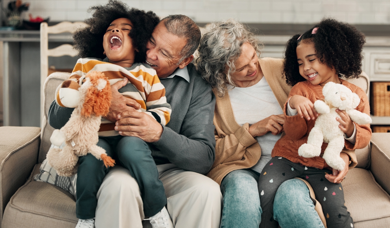 Children laughing or family with grandparents and grandkids bonding in the living room of their home