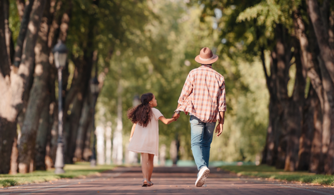 girl holding hands with grandfather and walking in park