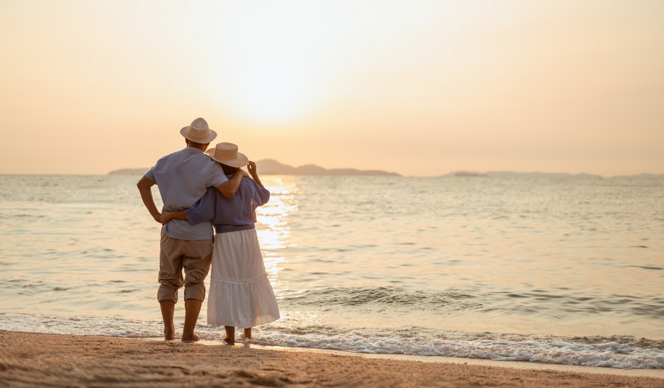 A couple standing on the beach at sunset