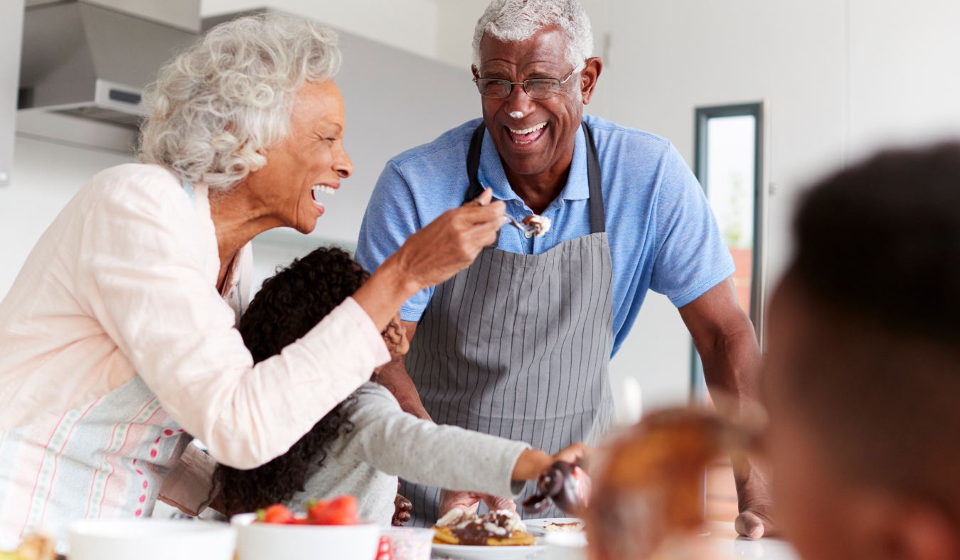 Grandparents In Kitchen With Granddaughter Making Pancakes Together
