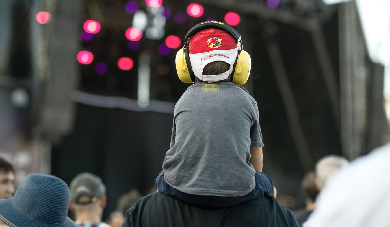 hearing protection with people child wearing protective earmuffs during concert
