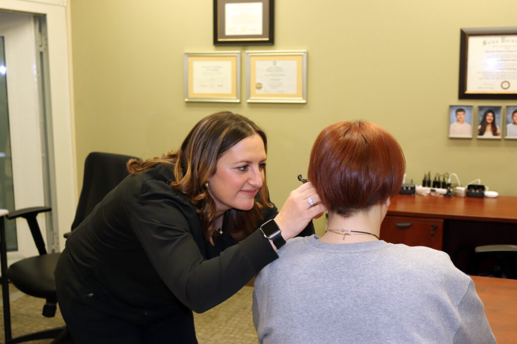 audiologist looking in patients ear with otoscope office 2