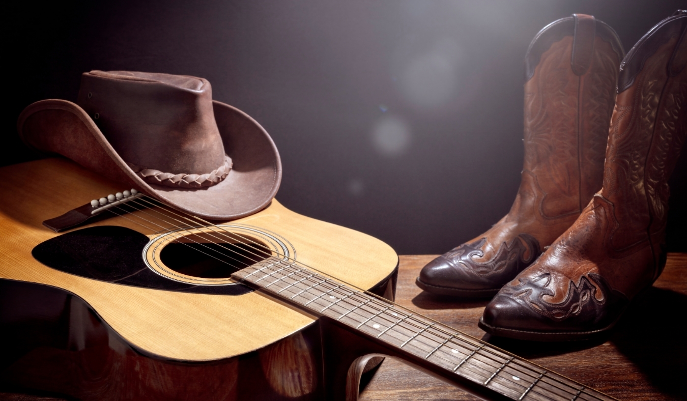 Country music festival live concert with acoustic guitar cowboy hat and boots background